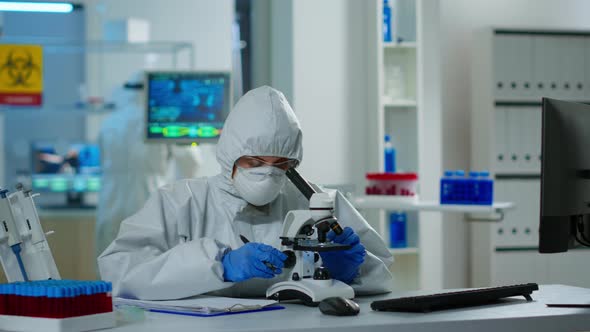 Medical Research Scientist in Ppe Suit Conducting DNA Experiments Under Microscope