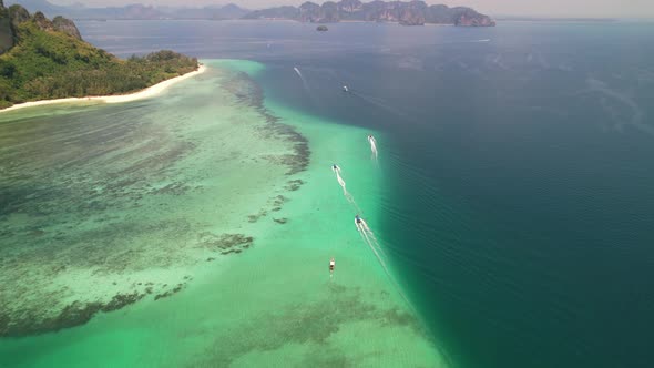 aerial top down view of  thai longtail boats motoring through coral reefs transporting tourists from