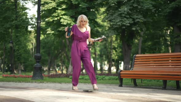 Elegant Woman Walking in Sunny Park Dropping Book Sighing