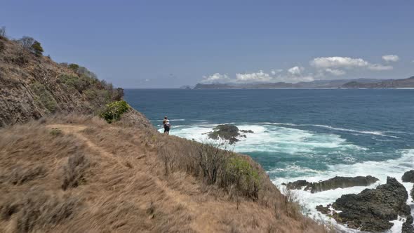 Couple Travelers on Peak of Summit Admiring Ocean Waters in Lombok, Indonesia