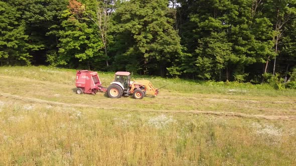 Tractor Pulling A Hay Baler Machine At The Farmland In Rural County Of Leelanau, Michigan. aerial