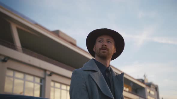 Portrait of Young Redhead Stylish Handsome Hipster Man with Hat on Sea Port Background During Sunset