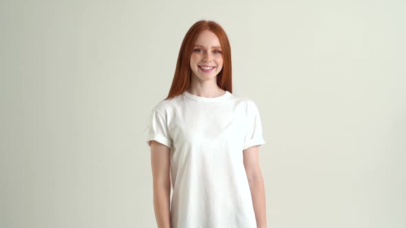 Portrait of Positive Pretty Young Woman Smiling and Looking at Camera Standing on White Isolated