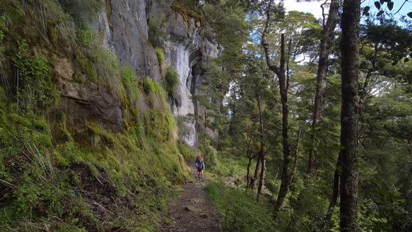 Static, hikers approach alongside rock wall Fiordland, Kepler Track New Zealand
