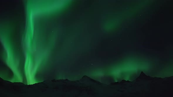 The northern lights filmed in real time over mountain landscape on the island Kvaløya near Tromsø in