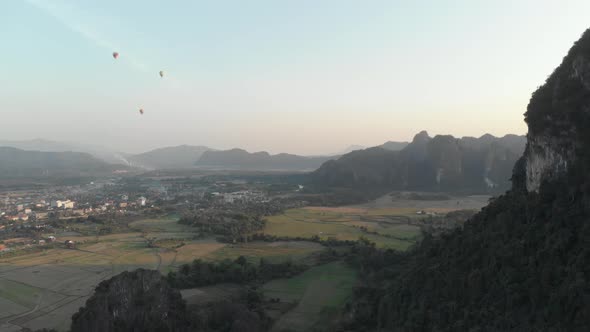 Aerial: Vang Vieng backpacker travel destination in Laos, Asia. Hot air balloons