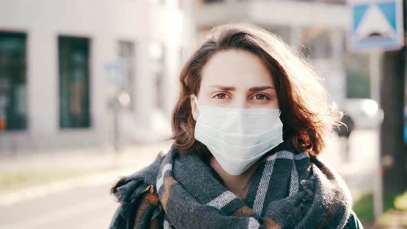 A Woman in a Medicine Mask Stands on the Street and Looking at the Camera.