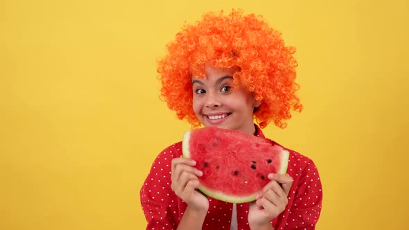 Surprised Teen Girl in Orange Hair Wig Showing Tongue and Biting Water Melon Slice Watermelon