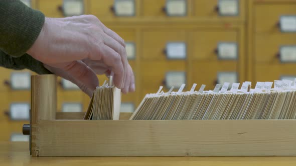 A Male Hand Searching Cards in Old Wooden Card Catalogue