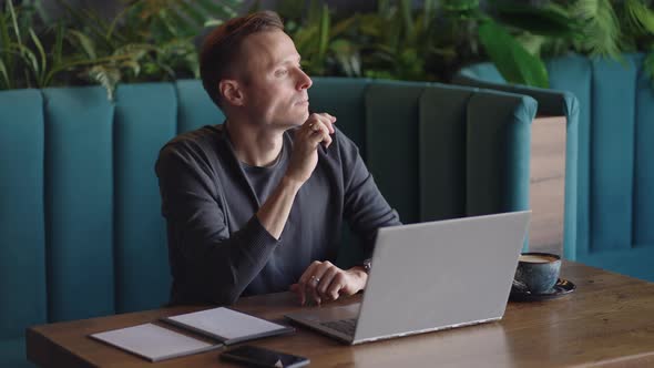 Thoughtful Serious Young Man Student Writer Sit at Home Office Desk with Laptop Thinking of