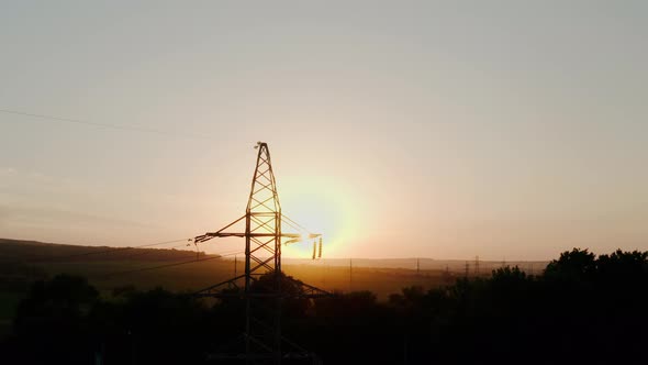 Aerial Drone View of Silhouettes High Voltage Steel Power Pylons in Field on Sunrise