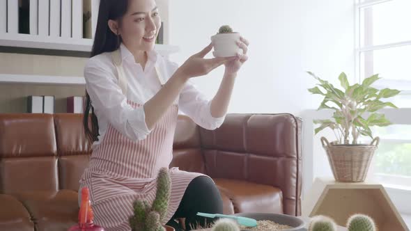 Young woman planting in the flower pots at home.