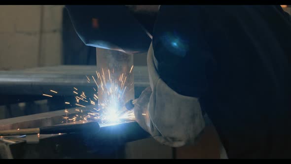 Welder welding metal parts in a workshop