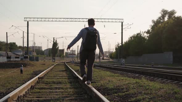 Man Walks Along the Train Tracks and Raises His Hands Up Feeling Freedom