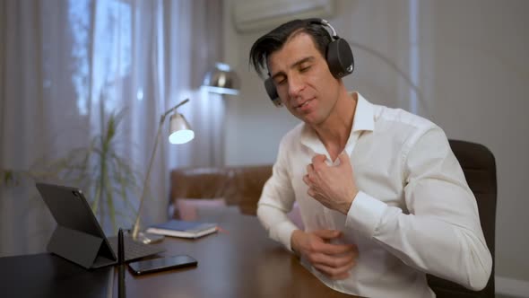 Young Middle Eastern Man Putting on Headphones and Turning on Webcamera Sitting in Home Office