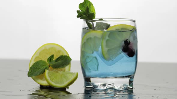 Adding Leaves of Mint in a Glass with Cold Drink, Lime, Lemon, Currants, Ice