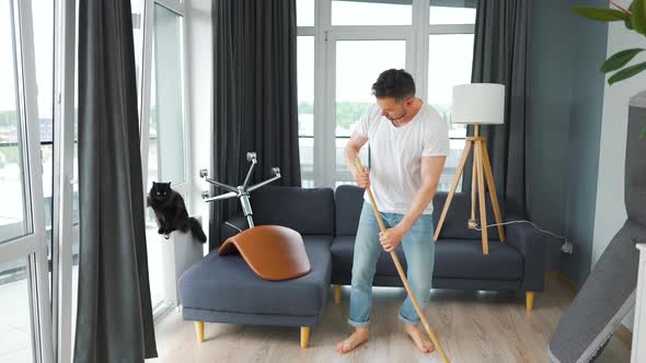 Man Cleaning the House and Having Fun Dancing with a Broom and Singing