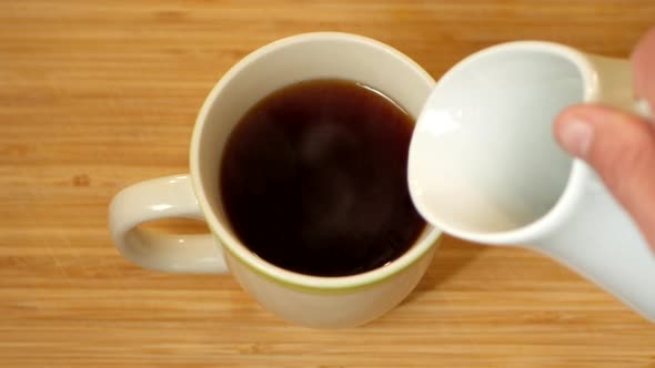 Milk being poured into a cup of tea. TOP DOWN ANGLE.