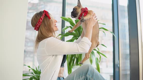 Young Woman Plays with a French Bulldog Dog