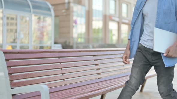 Young African Man Coming Sitting on Bench and Opening Laptop