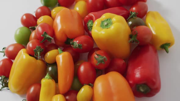 Video of fresh peppers and tomatoes spinning on white background