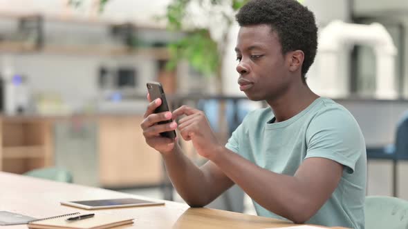 Young African Man Using Smartphone Browsing Internet