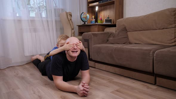 Happy Father and Son Have Fun at Home Lying on the Floor in the Living Room