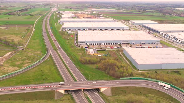 Aerial Shot of Industrial Warehouse Storage Building Loading Area where Many Trucks Are Loading Unlo