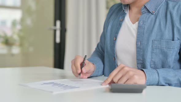 Close Up of Male Making Calculations Writing on Paper