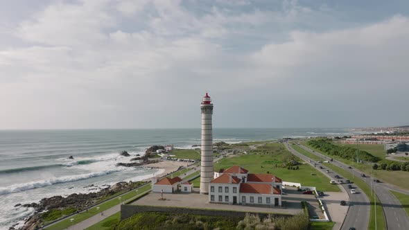 Lighthouse of Leça da Palmeira, aerial view. Busy road and waves at the sea.
