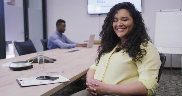 Portrait of smiling biracial businesswoman looking at camera in modern office