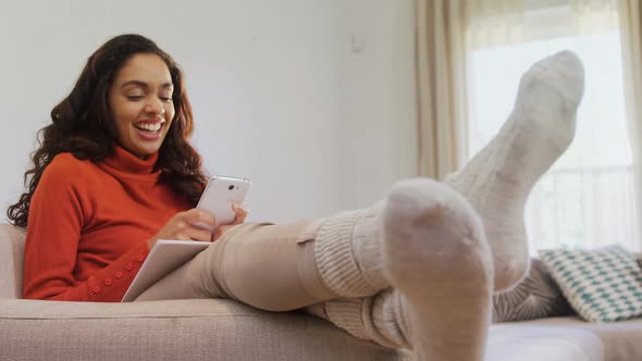 Woman sitting on sofa laughing while using her mobile phone 4K 4k