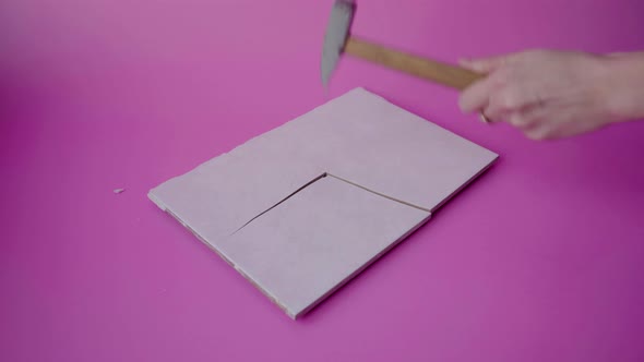 A hammer in the girl's hand breaks ceramic tiles into pieces