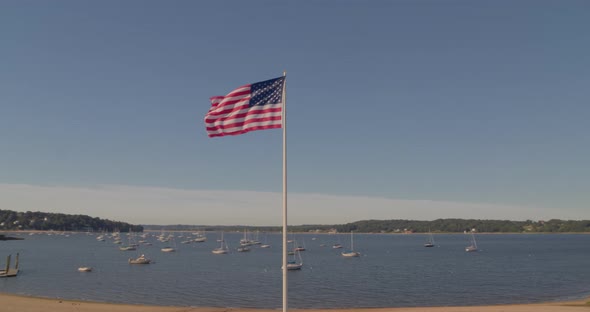 Aerial Pan of an American Flag at a Memorial Park and Boats Anchored at Harbor