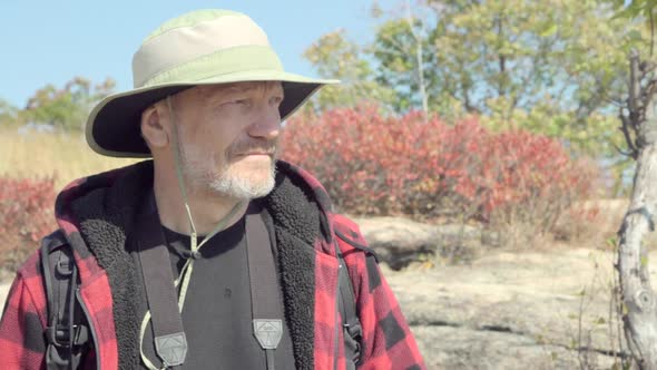 An older hiker looking through binoculars while on a scenic hike in the mountains