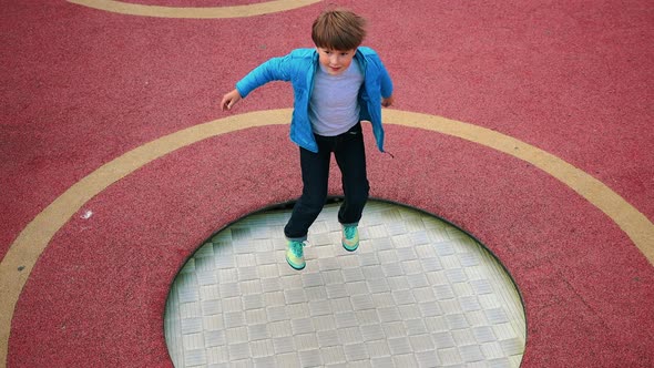 A Little Boy Jumping on the Trampoline on the Playground