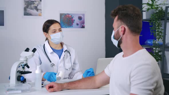 Therapist is Communicating with Patient in Clinic Answering and Measuring Temperature