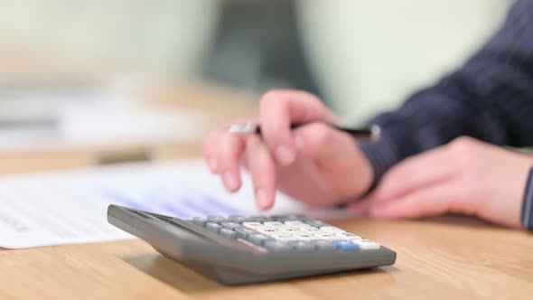 Close Up of Using Calculator and Checking Financial Documents 