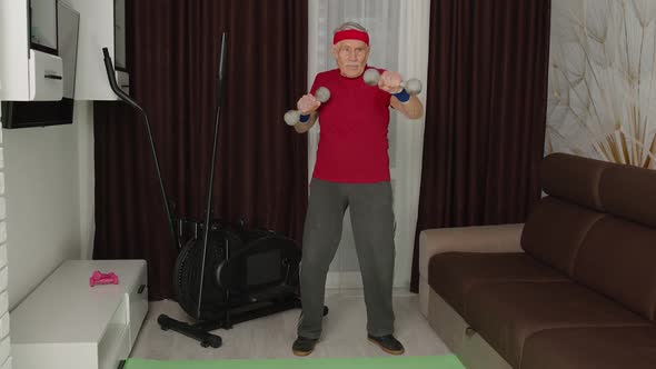 Senior Man Doing Vitality Workout Weightlifting Exercises with Dumbbells at Home During Coronavirus