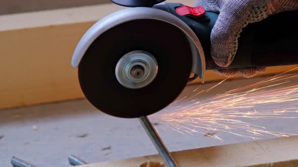 A builder's hands in work gloves cut a metal hairpin with an angle grinder electric tool. Preparatio