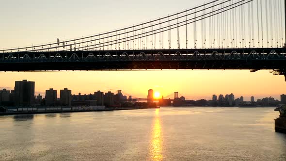 An aerial time lapse of the East River at sunrise. The drone camera dolly in under the Manhattan Bri