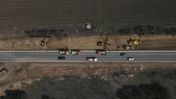 Excavator Digging Ground and Load It Into Dump Truck on Road