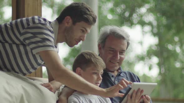 Boy with father and grandfather using digital tablet