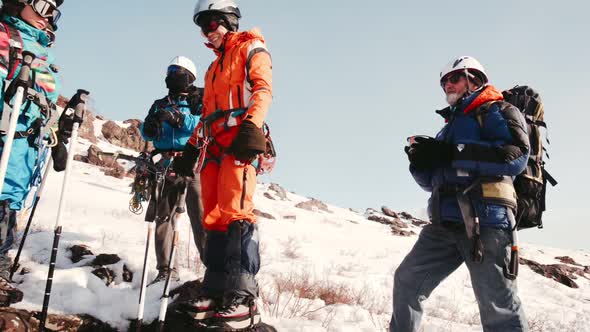 Group of Climbers Standing and Drinking Tea From a Thermos Bottle