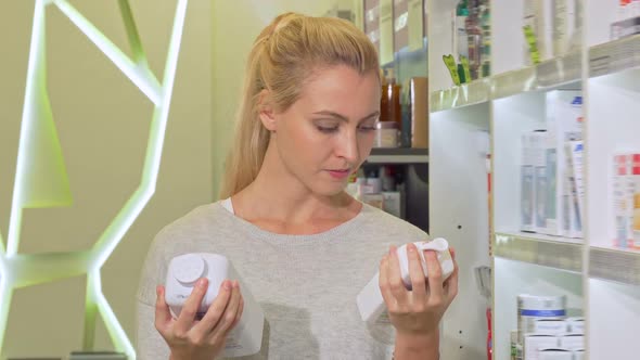 Beautiful Woman Looking Confused, Choosing Between Two Products at Pharmacy