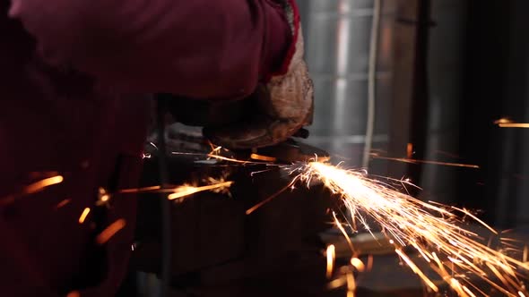 Craftsman grinding metal with grinder in vice