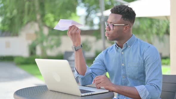 African Man with Laptop Flying Paper Plane Outdoor