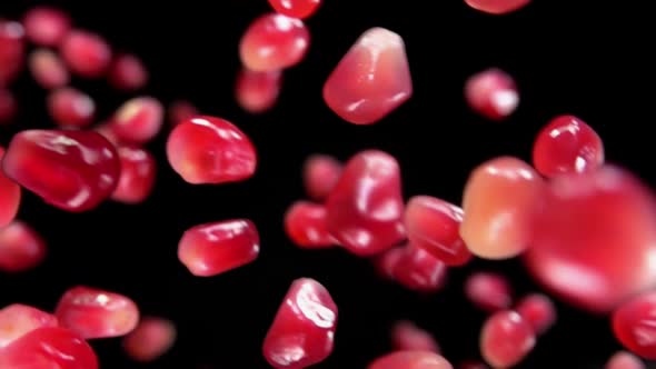 Closeup of Juicy Red Ripe Pomegranate Grains Bouncing on the Black Background