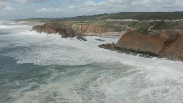 Flying towards waves from a wild sea slamming on rocky cliffs