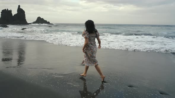 Young Woman in a Beautiful Dress Runs Along the Black Volcanic Black Sand Beach Benijo in the North